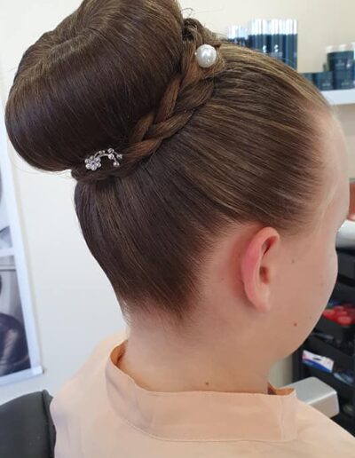 Chignon haut lisse sur cheveux bruns avec une fine tresse