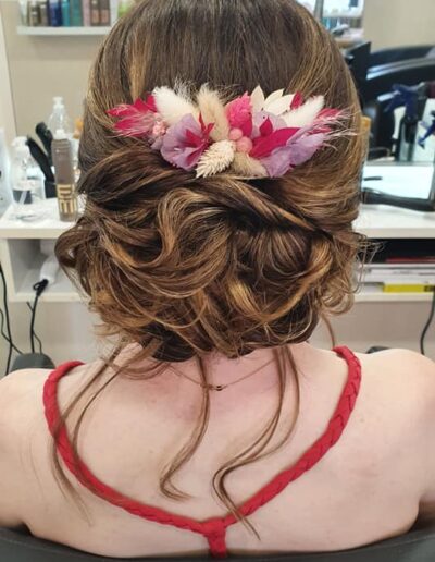 Chignon brun bas orné de fleurs roses et blanches