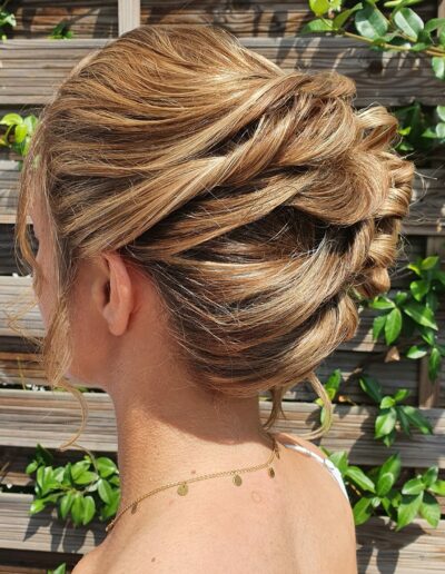 Coiffure blonde relevée avec mèches torsadées à l’arrière